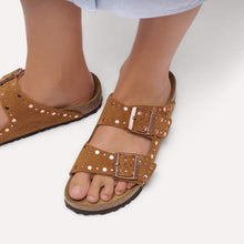Brown sandals with buckles worn by a person on a white background
