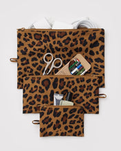Three leopard-print zip pouches in different sizes arranged, with storage for various small items visible in the compartments.