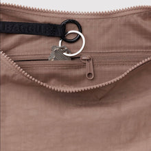Close-up of a brown bag with a zipper, key, and black strap.