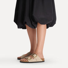 Person wearing cork sandals with gold buckles styled with black dress