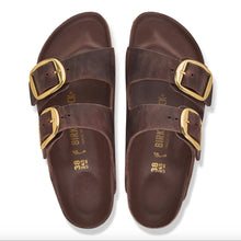 A pair of dark brown double-strap leather sandals with gold buckles