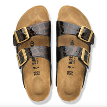 A pair of Birkenstock glossy black crocodile-embossed straps and gold-tone buckles