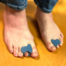 Feet with blue toe separators on a wooden floor