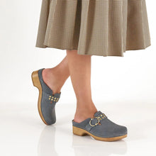 Blue clogs with gold buckles worn with a plaid skirt 