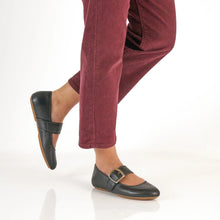 Person wearing maroon pants styled with black leather mary janes