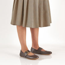 Brown flat mary janes with gold buckles styled with a plaid skirt 