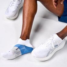 Person wearing white running shoes and socks with blue accents 