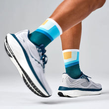Colorful socks with blue, green, and orange pattern worn with white and gray athletic shoes