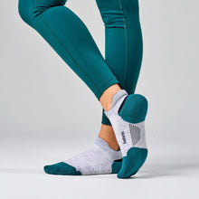 Person wearing green leggings and gray socks with green accents