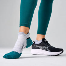 Person wearing green leggings, gray socks, and black running shoes