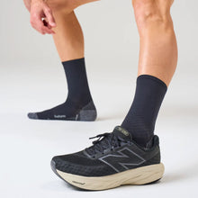 Person wearing black socks and New Balance running shoes