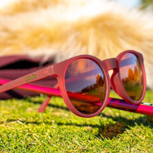 red sunglasses with reflective lenses on a grassy surface