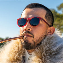 Man wearing red sunglasses and a fur-lined coat outdoors