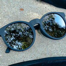 Black sunglasses with reflective lenses on a concrete surface