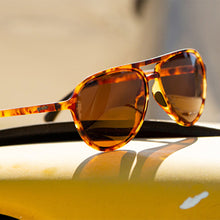 Tortoiseshell sunglasses on a reflective surface with a blurred background