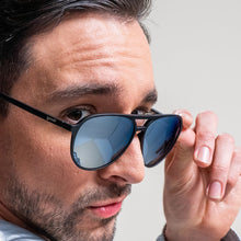 Man holding a pair of sunglasses with a neutral background