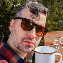 Man wearing sunglasses with a blurred background and a coffee cup in the foreground