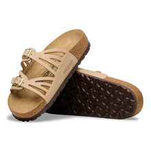 Pair of beige sandals with brown soles on a white background