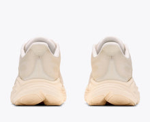 A pair of athletic running sneakers shown from the back, featuring a thick cream and beige sole
