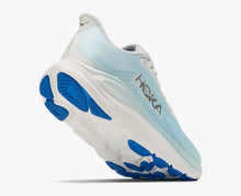 A woman's Hoka running shoe in light blue and white with bright blue accents on the sole