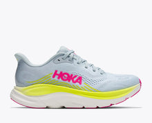 A Hoka running shoe in light blue and white with a bright neon yellow midsole and pink HOKA branding on the side