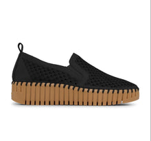 A black slip-on platform shoe with a textured knit upper and a chunky tan sole