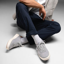 Person wearing gray sneakers styled with dark pants