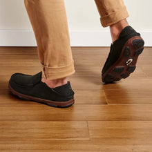 Person wearing black loafers on a wooden floor