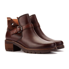 A pair of dark brown leather ankle boots with a chunky block heel, a buckle strap across the instep, and a rugged lug sole